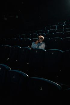 A couple enjoys a private cinema experience, seated closely in an empty theater.