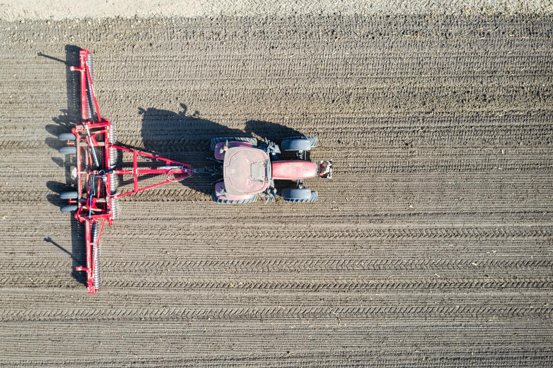 Drone shot of a tractor cultivating rows in a field, Plainview, MN.