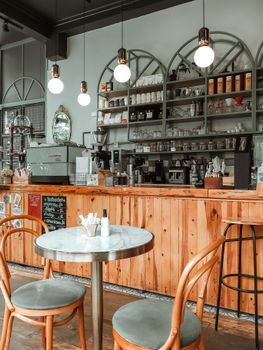 Charming coffee shop interior with a rustic wooden counter, shelves, and round table setup.