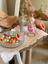 High angle of crop unrecognizable person bringing tray with multicolored dragee in glass bowl and creative ceramic flasks