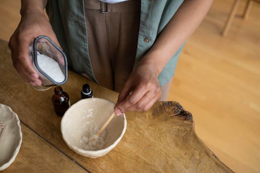 Close-up of hands mixing homemade natural body scrub in a bowl.