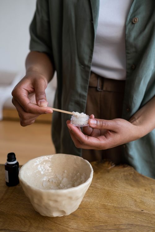 Free Close-up of hands transferring homemade cream into a small container on a wooden table. Stock Photo