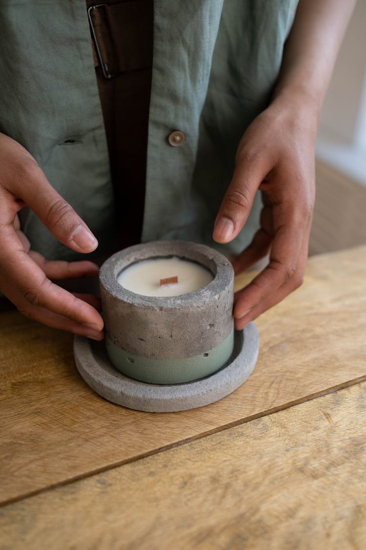 Person Touching A Cement Tea Light Candle Holder On Wooden Table