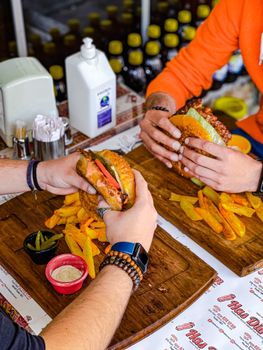 Two people eating burgers with fries at a restaurant, captured in a top view setting.