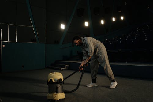 A Man in Coveralls Vacuuming in a Cinema