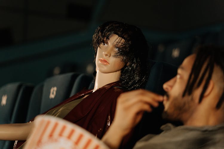 A Man Sitting Beside A Mannequin