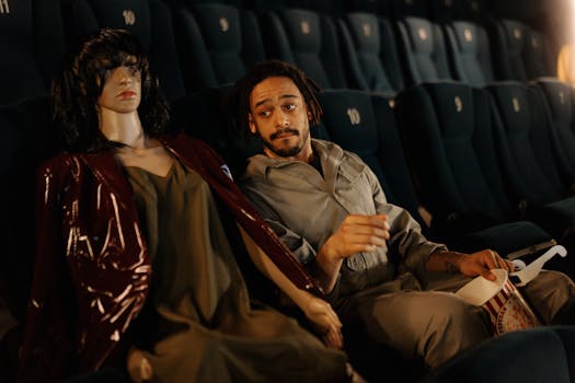 A man and a mannequin share a humorous moment in a cinema.