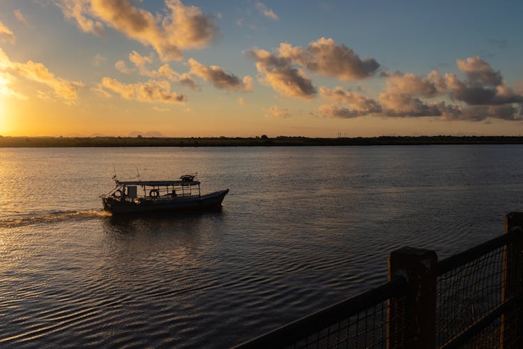 Boat Sailing On The Water At Dusk