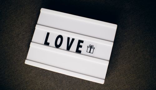 Free An illuminated lightbox displaying the word LOVE with a gift icon on a dark fabric background. Stock Photo