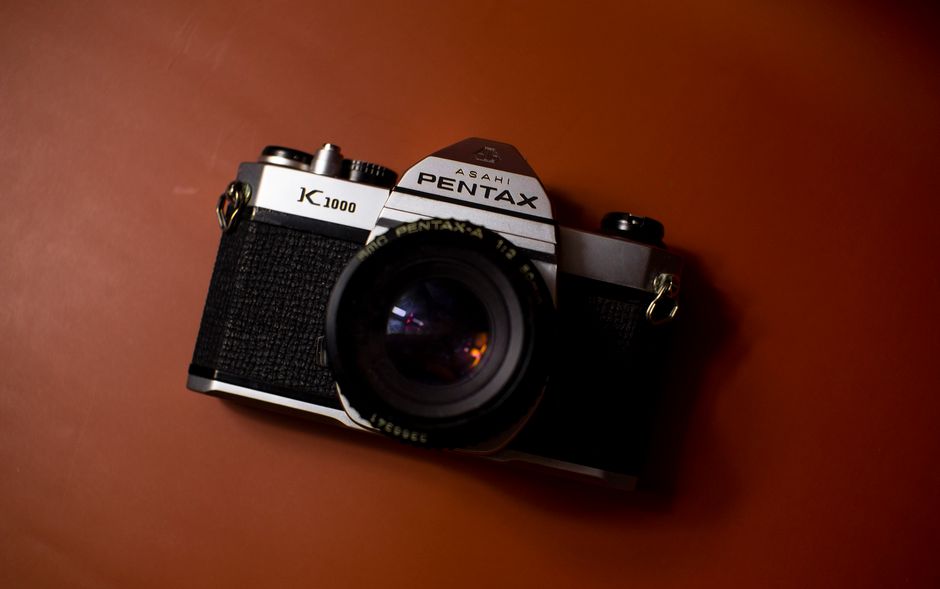Classic Pentax K1000 DSLR camera set on a brown surface, perfect for photography enthusiasts.