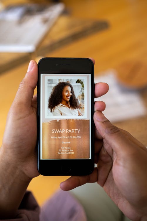 Free Close-up of hands holding smartphone displaying a swap party invitation. Stock Photo Free Close-up of hands holding smartphone displaying a swap party invitation. Stock Photo