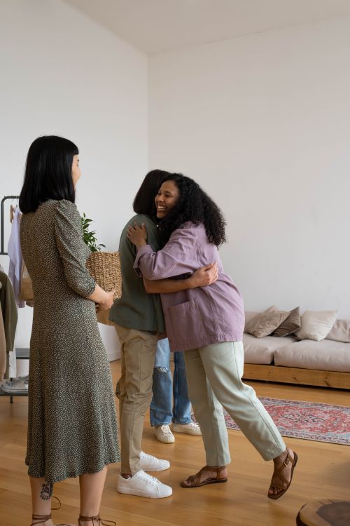 Free Friends embracing in a cozy living room, showcasing diversity and warmth. Stock Photo