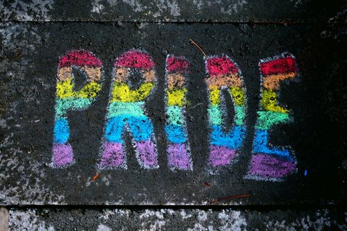 Free Vibrant rainbow chalk art spelling 'PRIDE' on pavement symbolizes inclusivity and diversity. Stock Photo