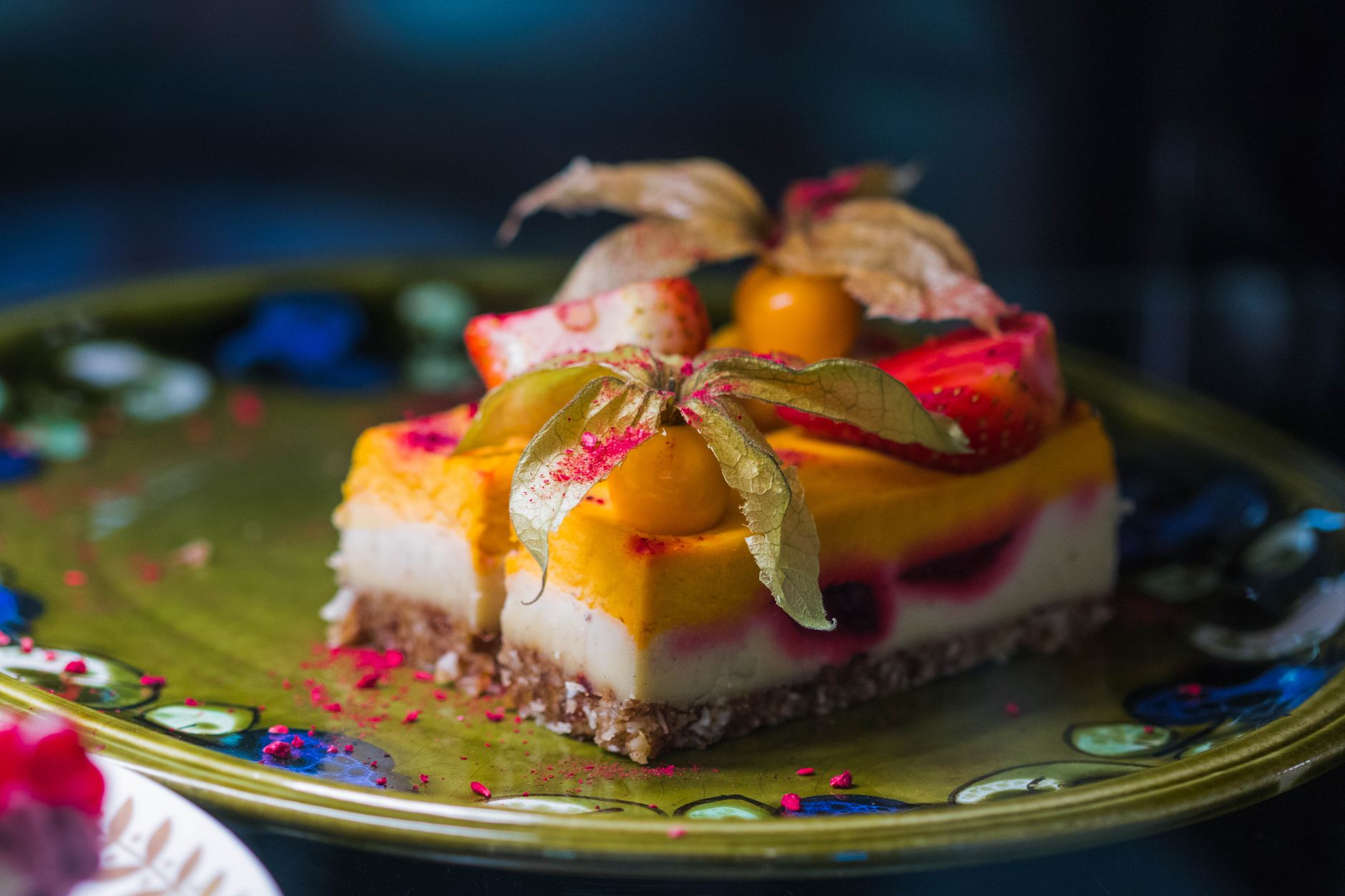 Sliced vegan cheesecake on a wooden cutting board with lemon zest garnish