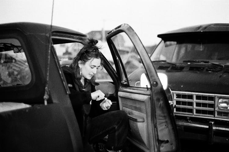 Woman Sitting On The Pickup Truck Lighting A Match