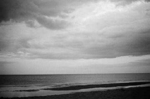 Grayscale Photography of Ocean Under Cloudy Sky