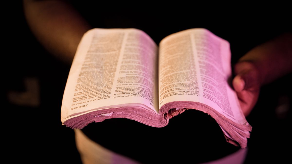 Hands resting on an open Bible - What Is a Christian?