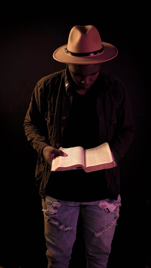 Free A Man in Black Jacket and Brown Hat Reading a Book Stock Photo