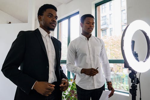 Man in White Long Sleeve Shirt Standing Beside Man in Black Suit