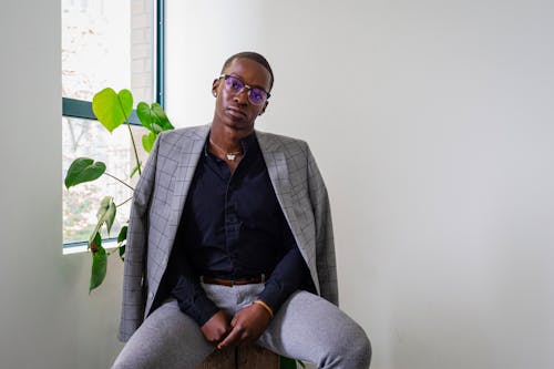 A Man in Black Long Sleeves and Gray Pants Sitting Near the Green Plants