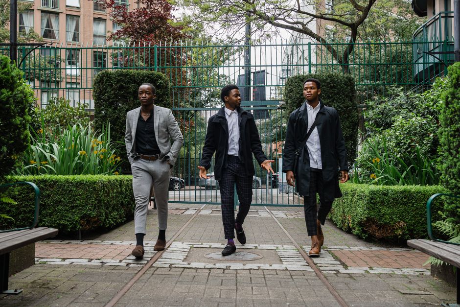 Three men in elegant suits are walking through an urban park, exuding confidence and style. Three men in elegant suits are walking through an urban park, exuding confidence and style.