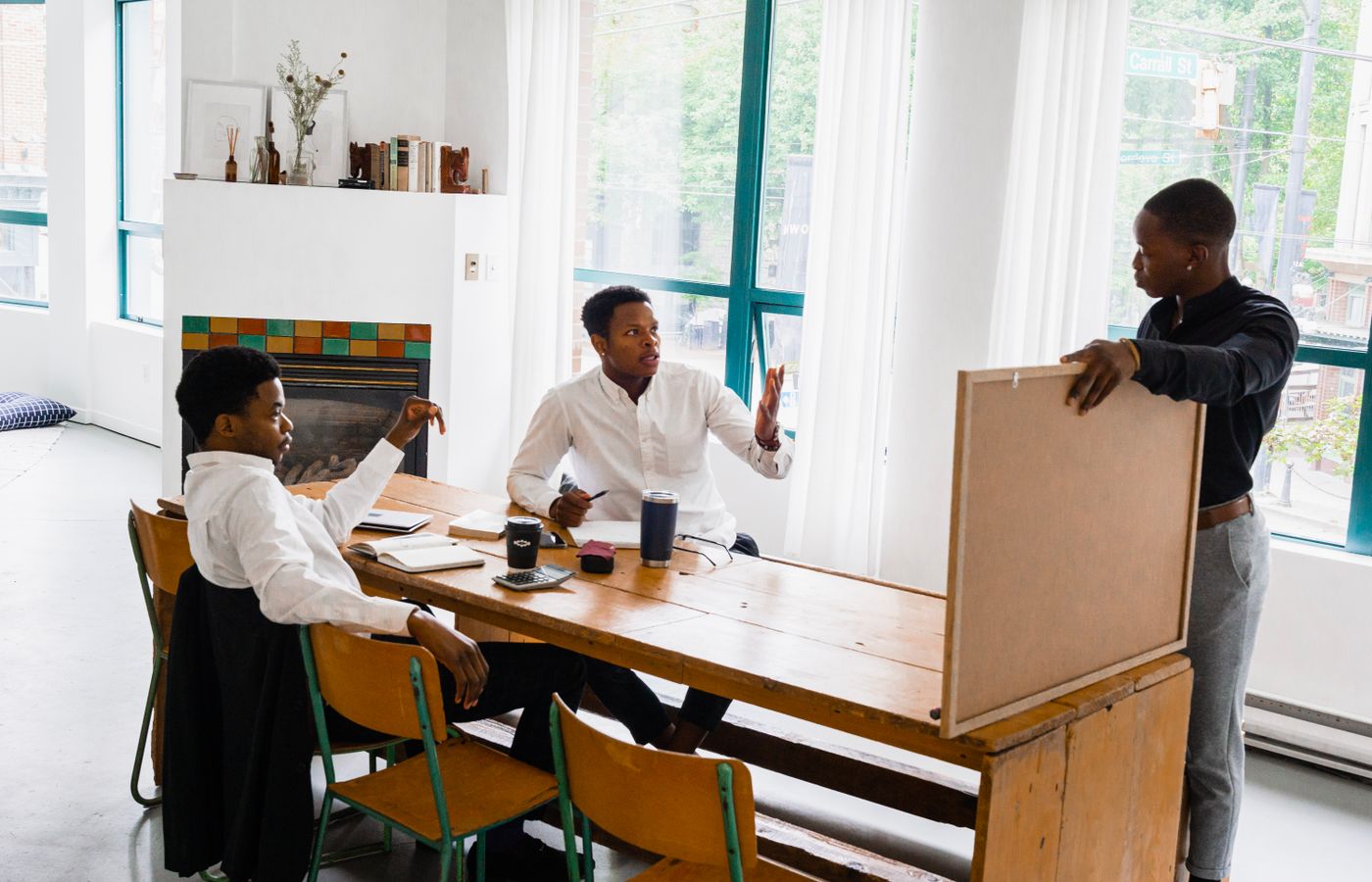 Three men discussing a project at a table in a bright office setting.