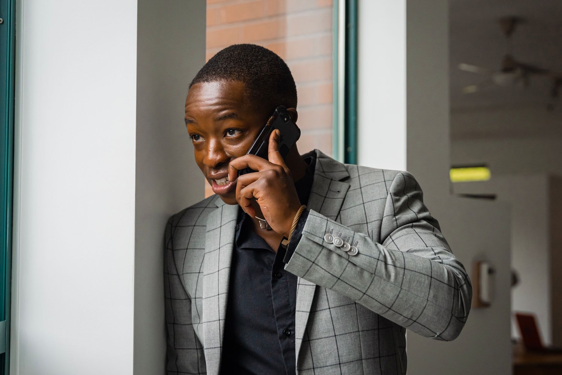 Businessman in gray suit talking on smartphone indoors