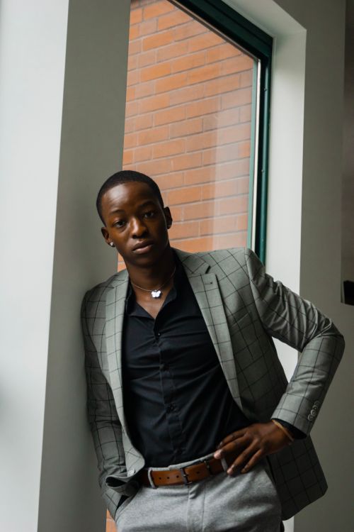 Free Elegant young man in business attire standing confidently by a modern window. Stock Photo