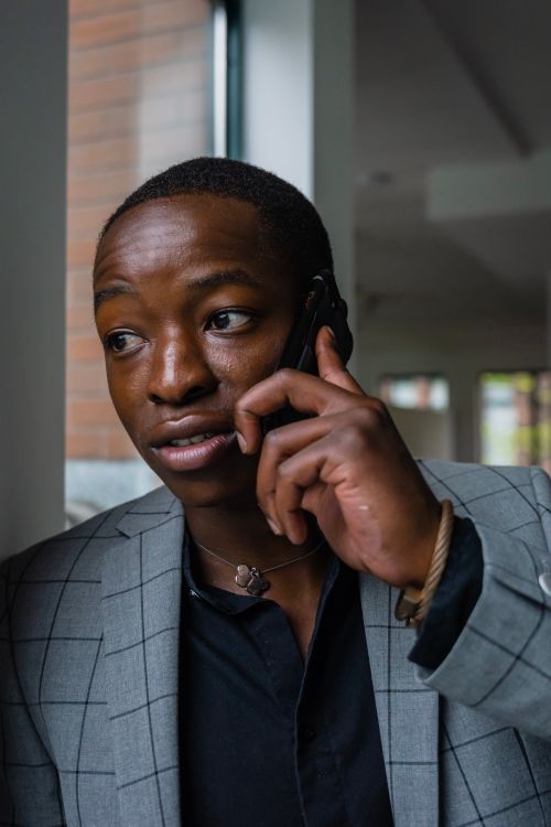 Free A well-dressed man in a gray suit is engaged in a phone call indoors. Stock Photo