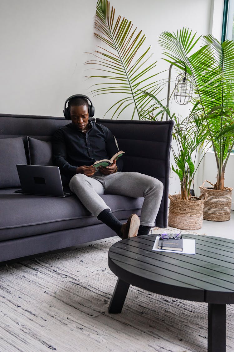 A Man With Headphones Reading A Book