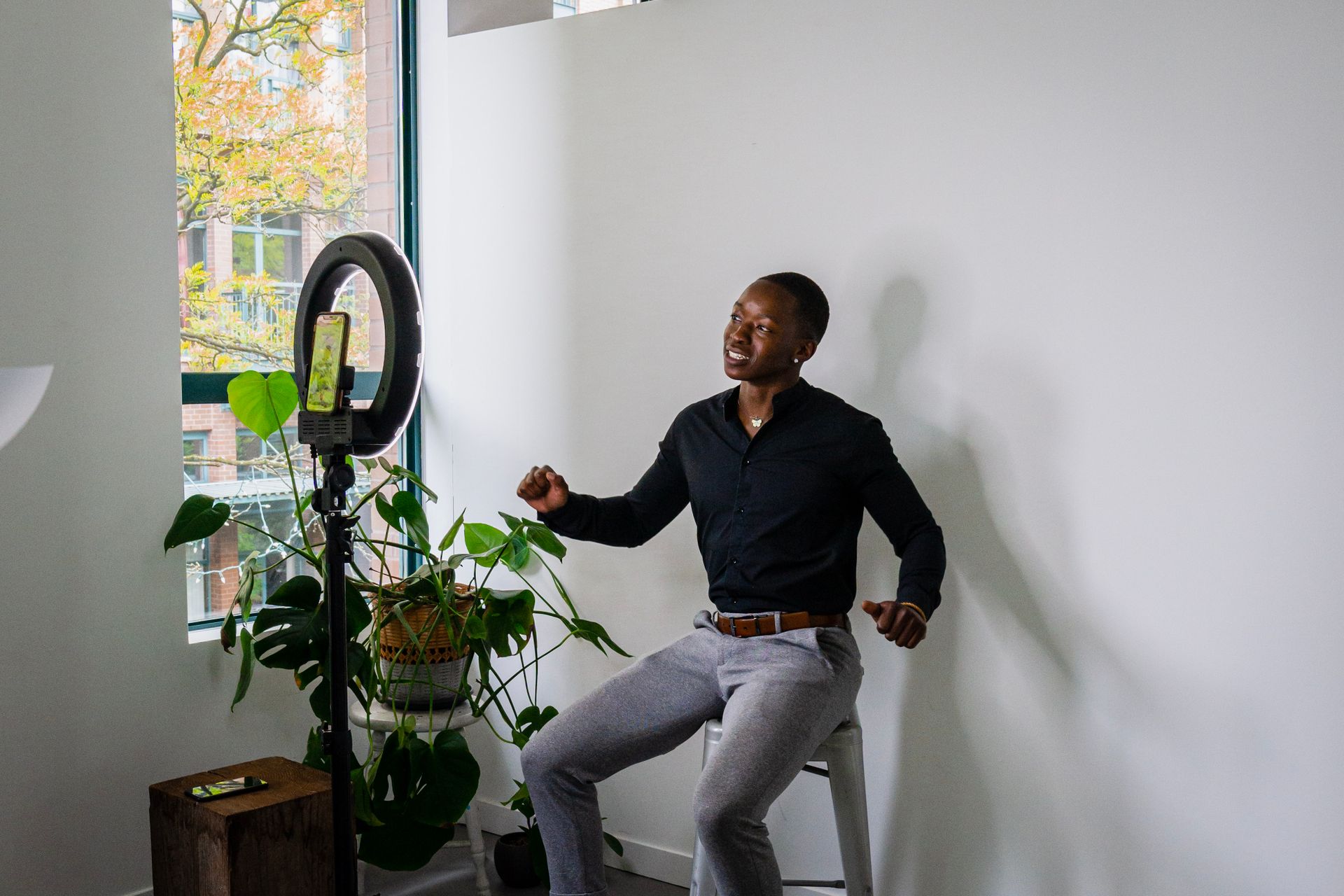 African American man recording a video with a smartphone and ring light in a modern room.