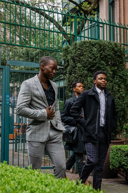 Free Group of young black men dressed in suits walking outdoors, conveying professionalism and friendship. Stock Photo