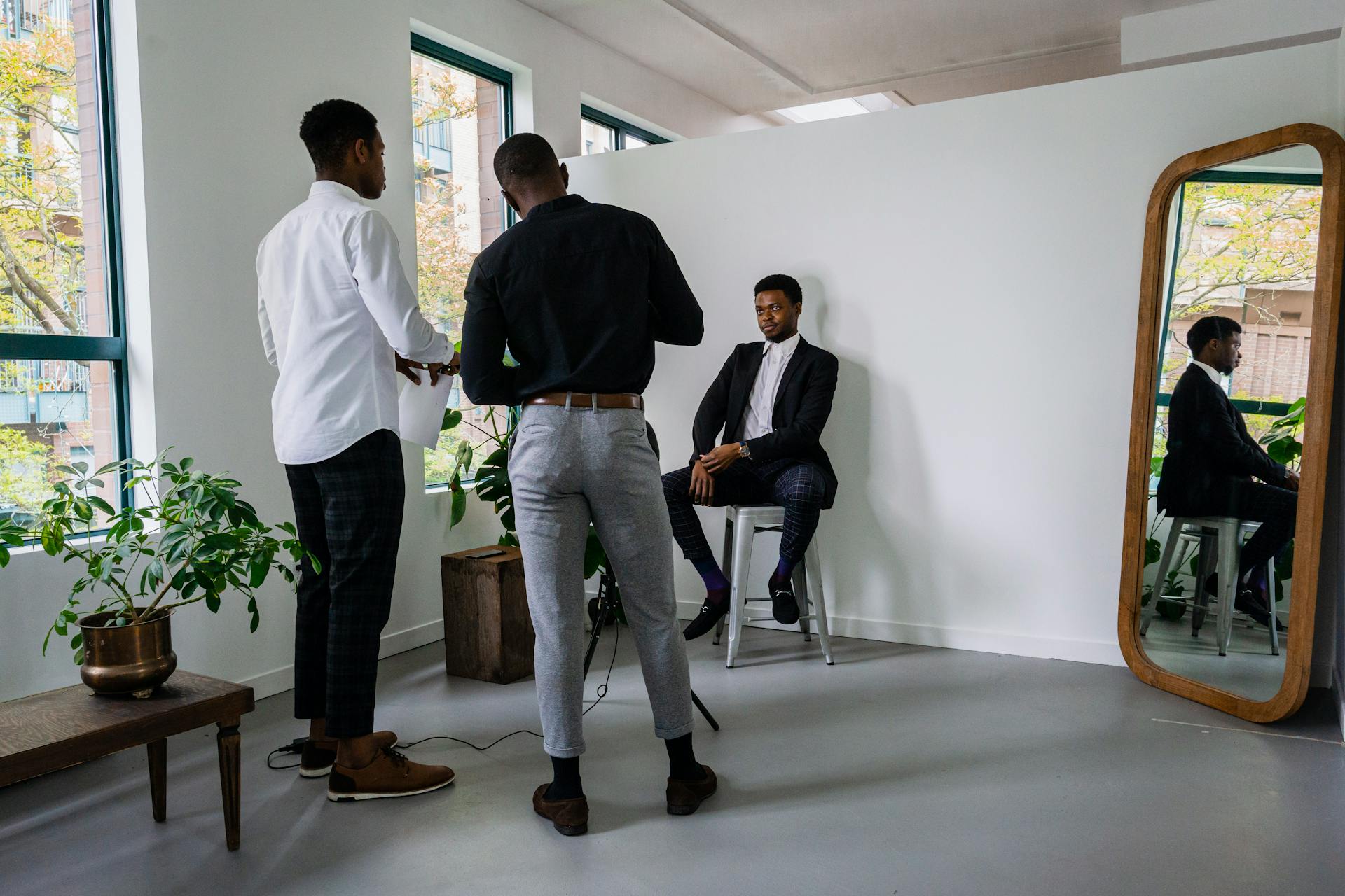 Businessmen preparing a portrait pose with mirror reflections in a modern indoor studio.