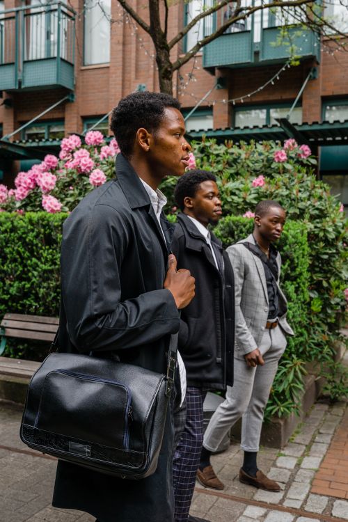 Free Three businessmen walking confidently in a lush city park. Business fashion and teamwork concept. Stock Photo