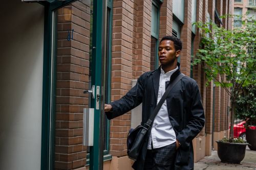 Free Young man in coat entering a brick building, showcasing urban life. Stock Photo