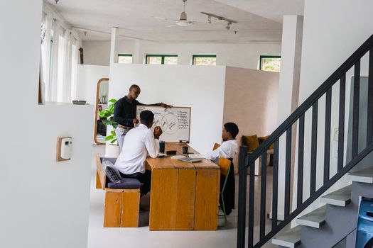 Three men engaged in a collaborative meeting in a contemporary office setting with a whiteboard.