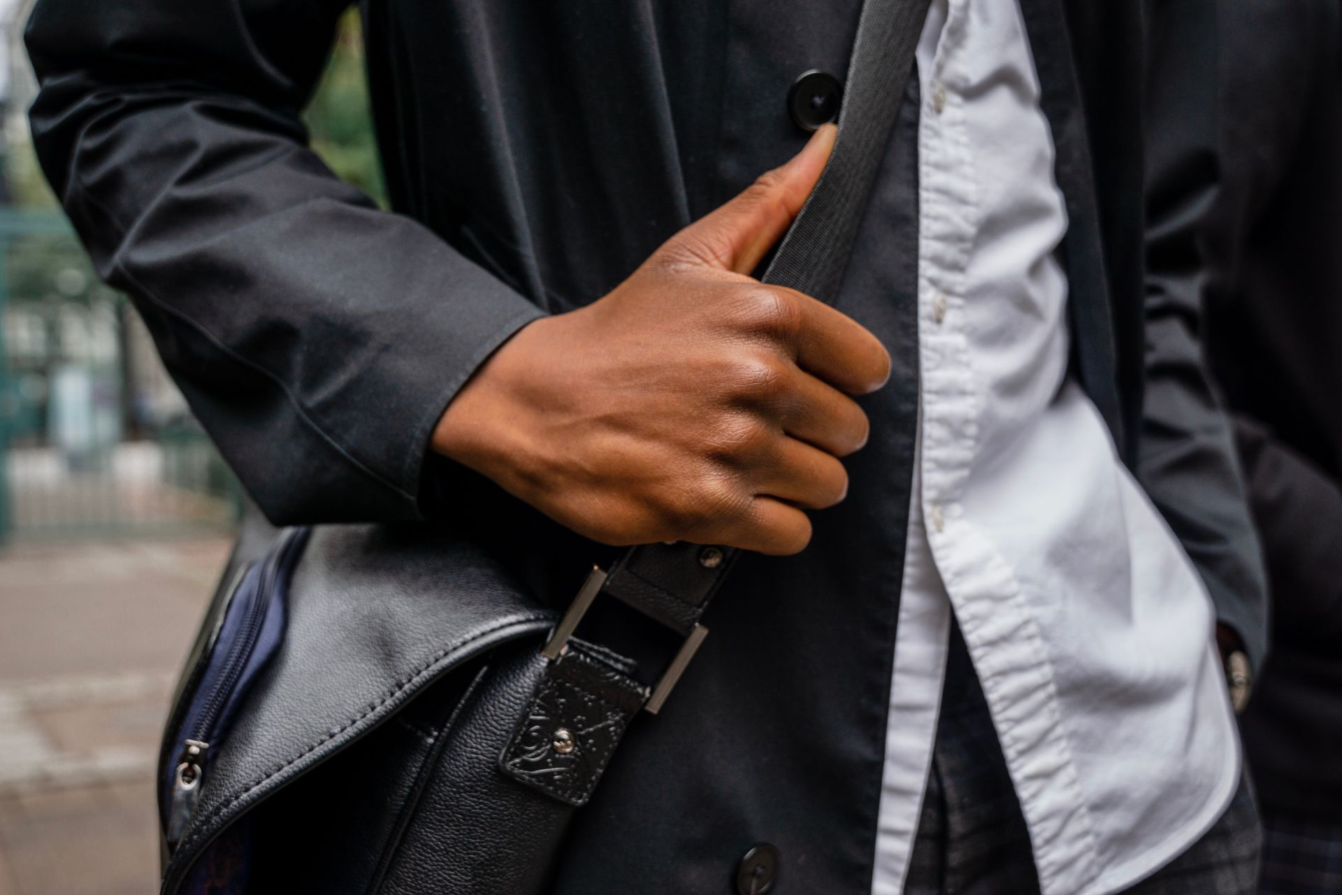 Close-up of a person holding a stylish leather bag, dressed in business attire.