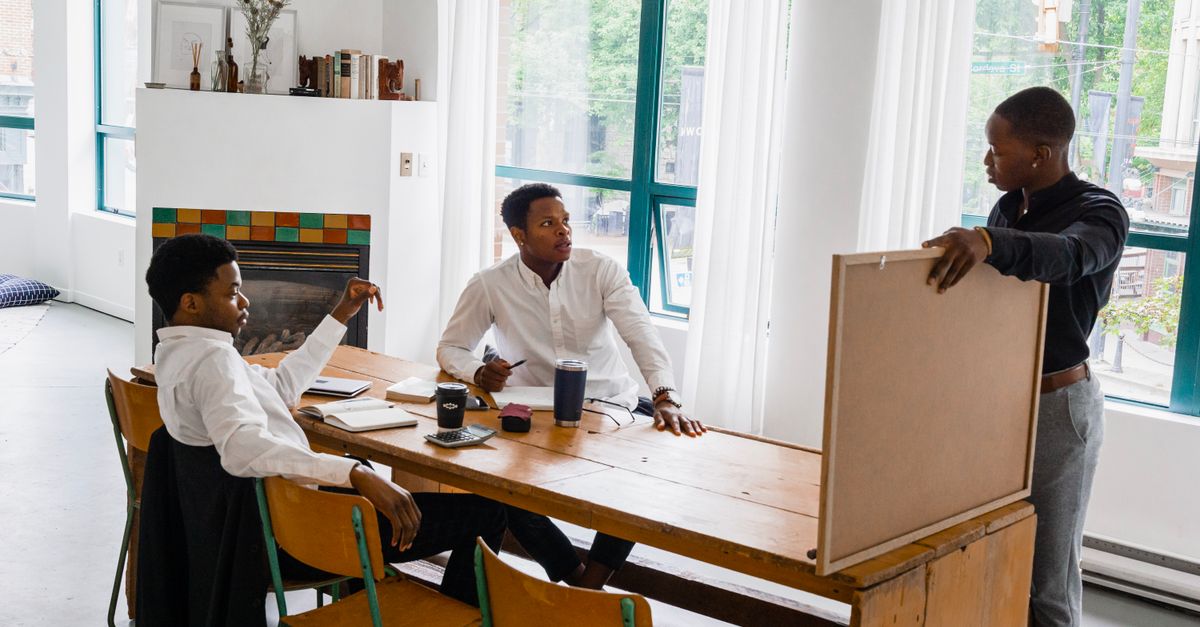 A group of young Ghanaian entrepreneurs brainstorming in a bright co-working space in Ho