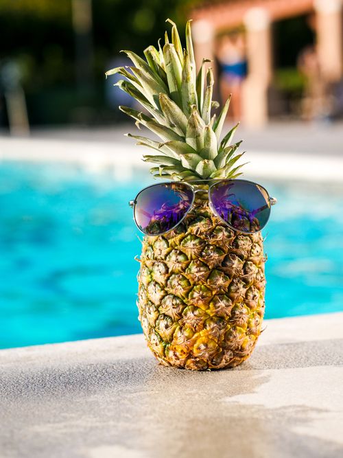 Free A vibrant pineapple wearing sunglasses by the pool, embodying summer vibes. Stock Photo