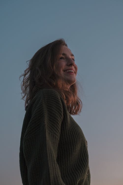 Low-Angle Shot of a Woman in Green Sweater Smiling