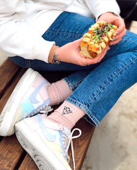A person holding a delicious taco while sitting outdoors in casual attire, enjoying a meal.