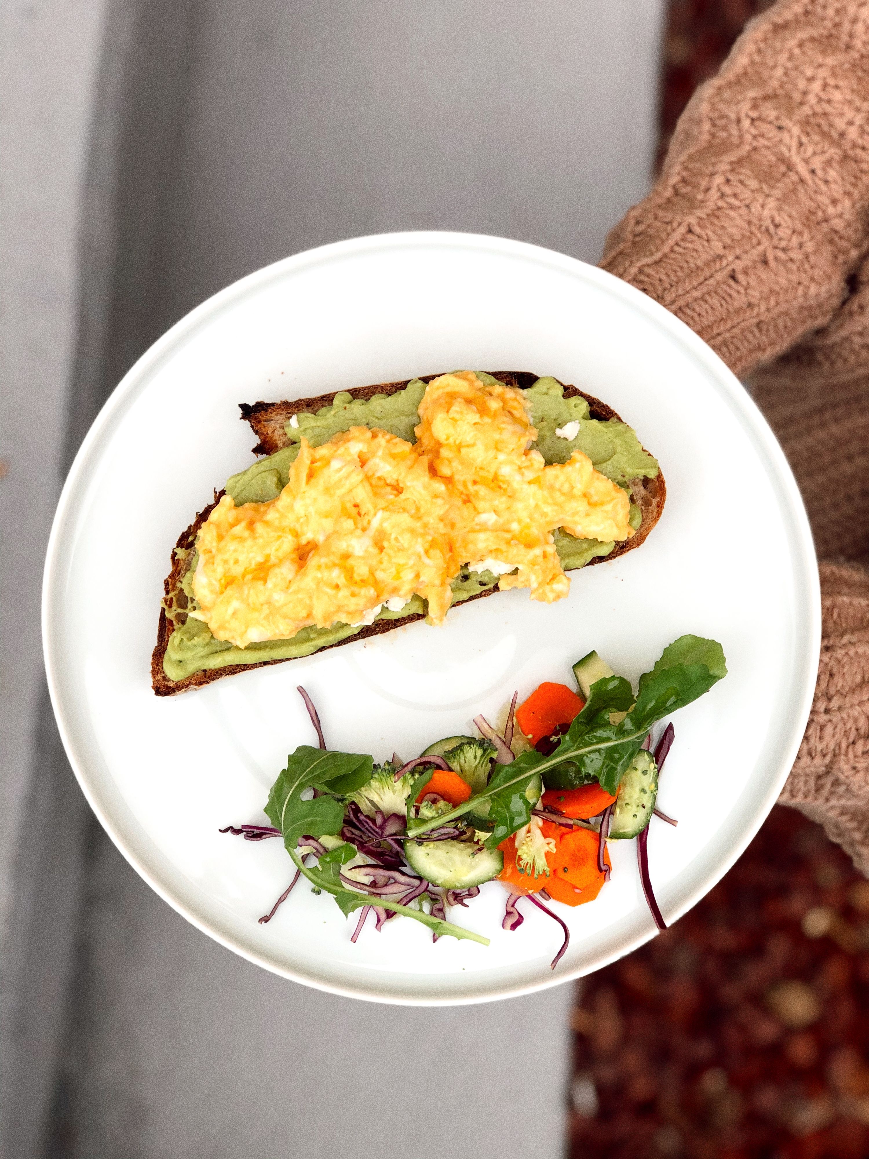 Appetizing avocado toast served with fresh salad on a white plate, ideal for brunch.
