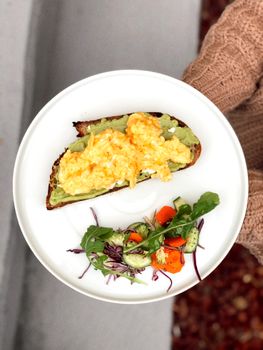 Appetizing avocado toast served with fresh salad on a white plate, ideal for brunch.