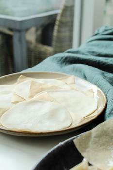 Dumpling wrappers on a plate ready for cooking, perfect for Asian cuisine.