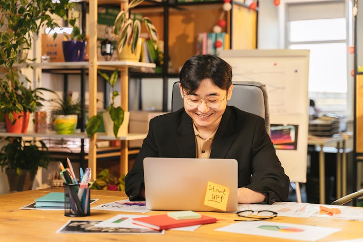 A Man In Black Suit Using A Laptop In The Office