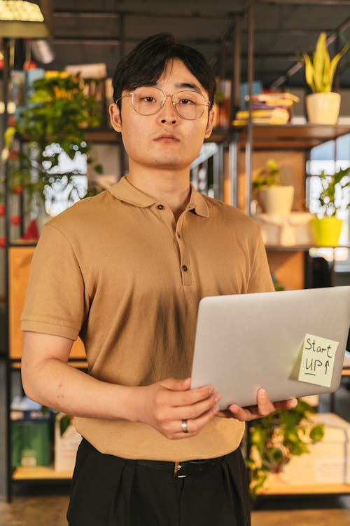 Photo of a Man in a Brown Polo Shirt Carrying a Laptop
