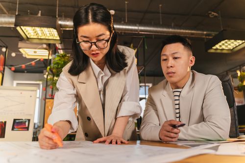Free Colleagues engaged in a discussion around project plans in a modern office. Stock Photo
