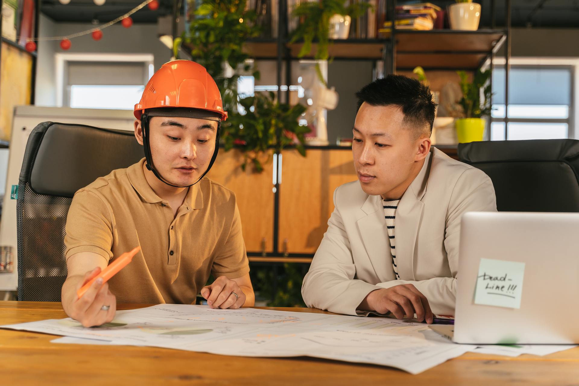 Construction manager and office worker reviewing plans in a modern office setting.