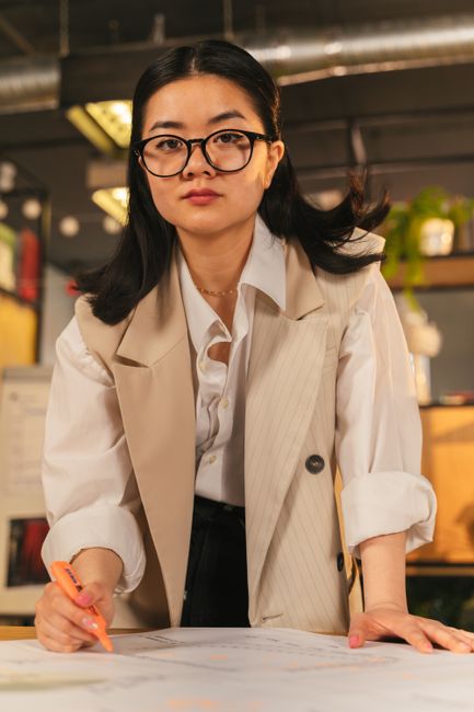 Focused female architect working on project plans in a contemporary office setting.