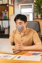 Man in Brown Shirt Wearing Gray Face Mask Sitting on Gray Chair
